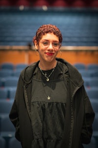a woman in a black jacket standing in an auditorium
