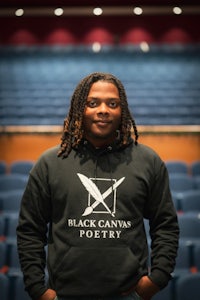 a man in a black hoodie standing in front of an auditorium