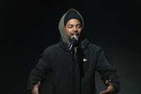 a man in a black jacket is holding a microphone