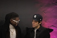 two men standing next to each other with hats on