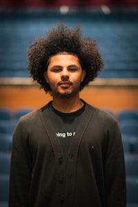a young man with afro hair standing in front of an auditorium
