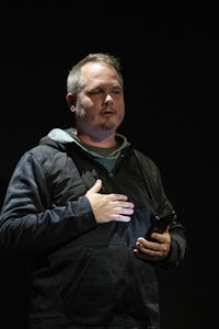 a man in a black hoodie holding a cell phone