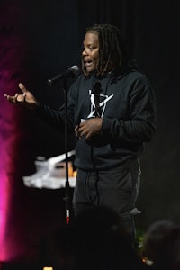 a man with dreadlocks standing in front of a microphone