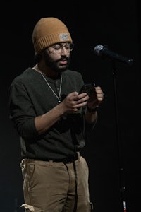 a man in a beanie is holding a cell phone