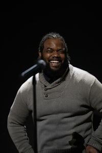 a man with a beard is smiling into a microphone
